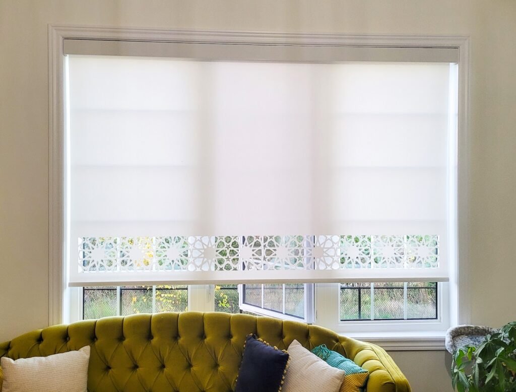 White roller shade over a window above a green velvet sofa