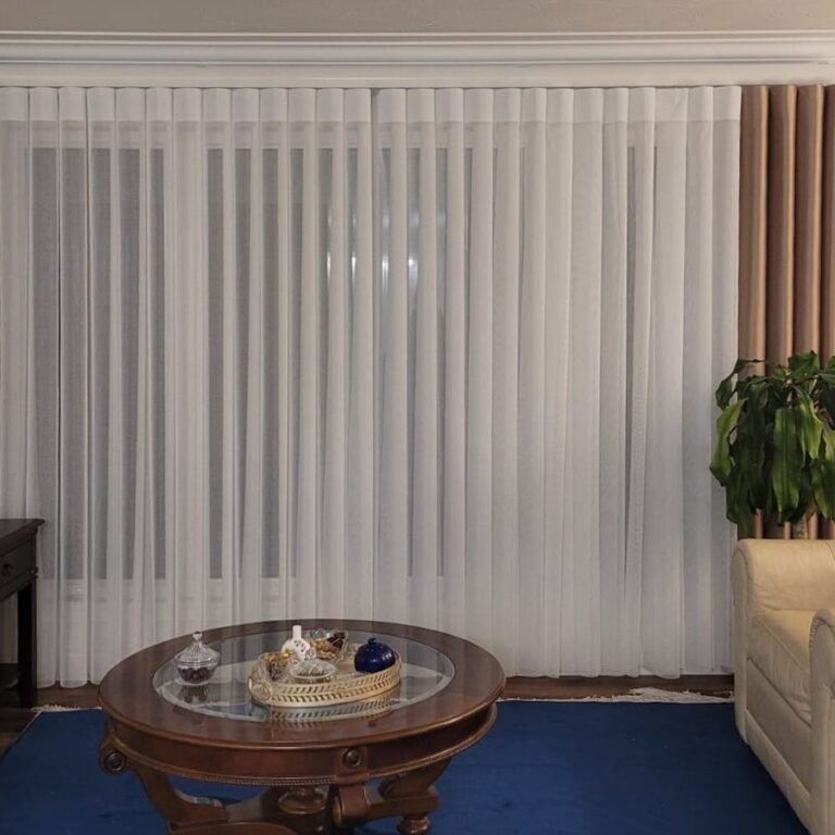 Vertical sheers across a large window beside a plant