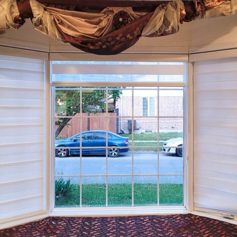 Honeycomb shades raised on a bay window with a street view