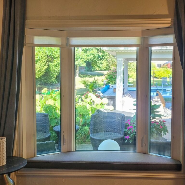 Roller shades raised on a bay window with a street view