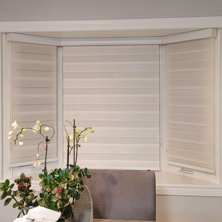Honeycomb shades on a bay window with an orchid