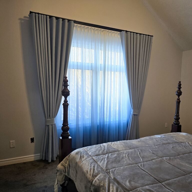 Blue-toned sheer curtains layered with grey drapery in a bedroom