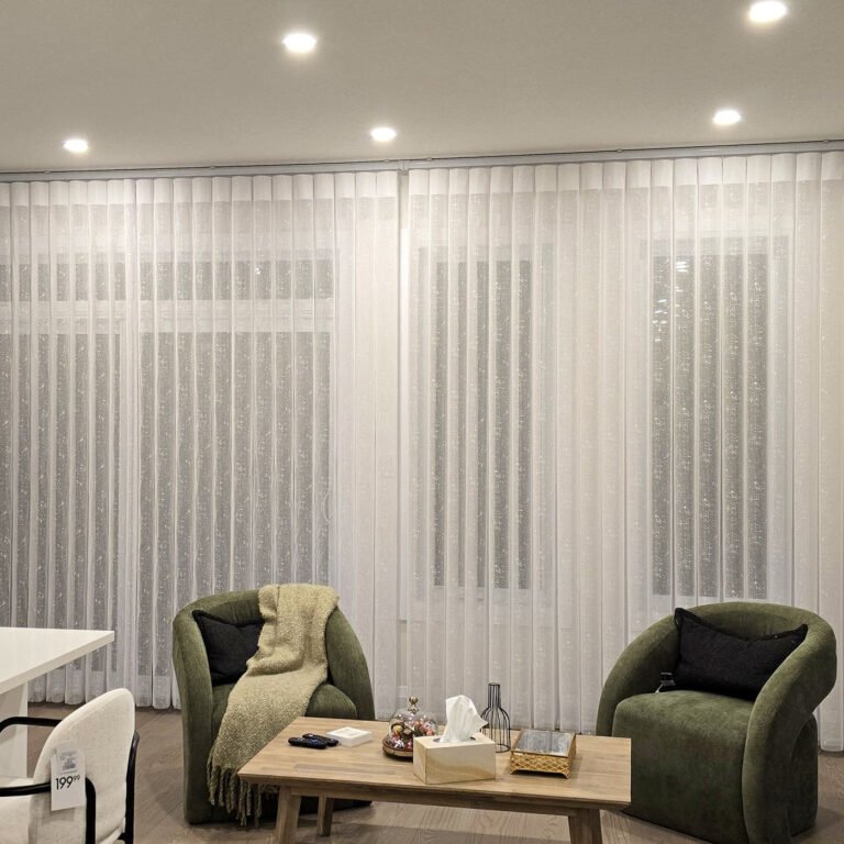 Vertical sheers in a family room with green armchairs