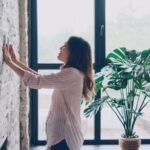 Homeowner by a large window with smart controls