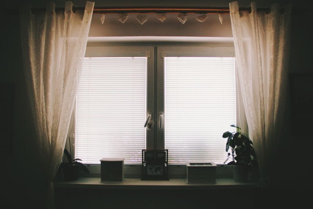 Cellular shades layered with sheer curtains